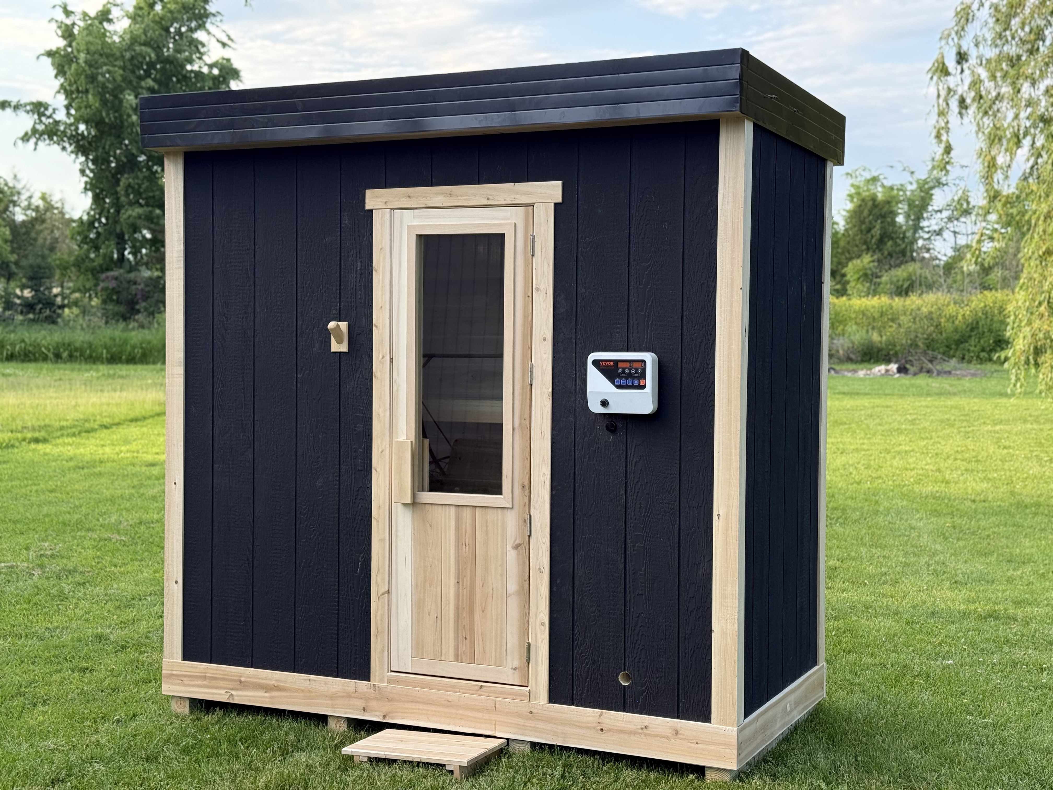 Charcoal-clad custom outdoor sauna with cedar trim